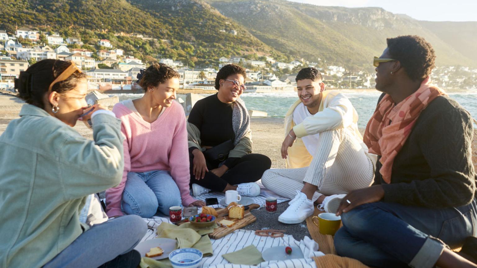 Grupo de amigos comiendo en la playa, Sudáfrica