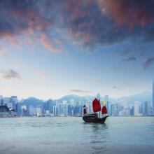 Barcos tradicionales de bambú navegan al anochecer en el Victoria Harbour, en Hong Kong