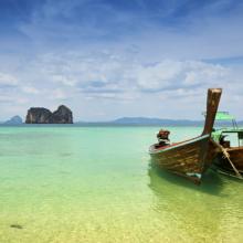 Barcos tradicionales tailandeses de cola larga varados en la playa, y al fondo, formaciones rocosas de caliza, en Trang, al sur de Tailandia