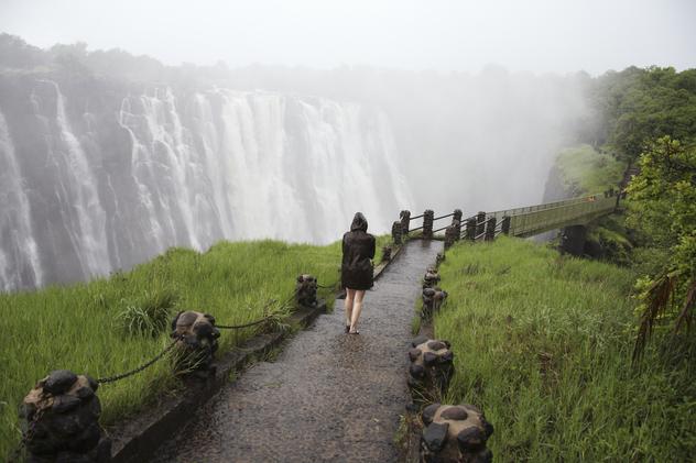 Mujer caminando hacia las cataratas Victoria. © David du Plessis / Gallo Images ROOTS / Getty Images